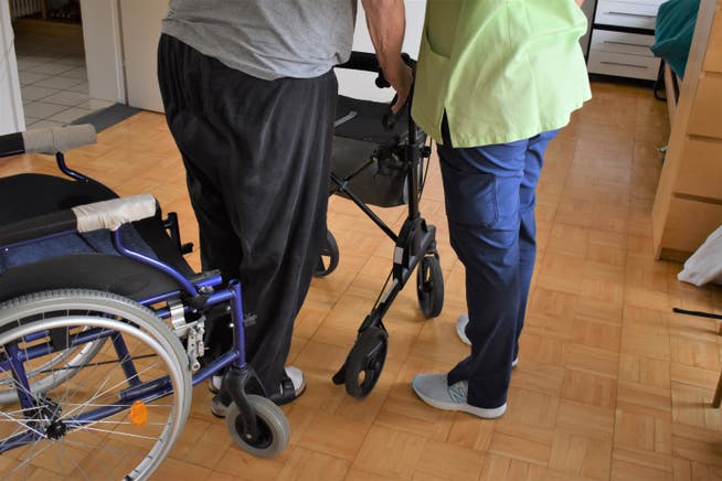 Spitex-Mitarbeiterin Silvia Böni begleitet den Kunden mit dem Rollator ins Badezimmer.