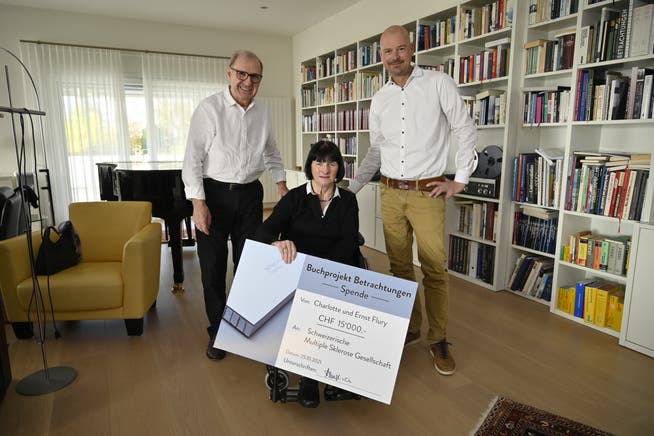 Ernst und Charlotte Flury übergeben Christoph Stamm von der Schweizerischen Multiple Sklerose Gesellschaft einen Check über 15'000 Franken aus dem aufgerundeten Erlös des Verkaufs des Bildbands Betrachtungen.