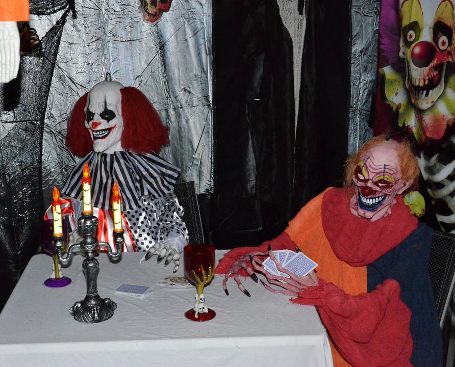 Clowns sitzen vor einem Glas Blut und spielen Karten.