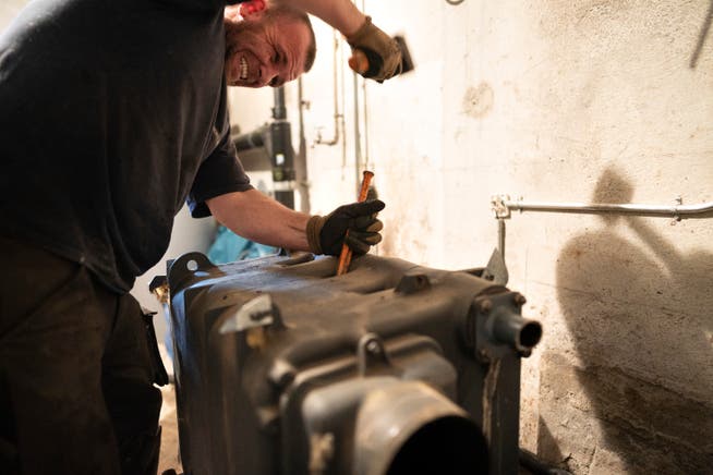 Ein Arbeiter demontiert einen Heizkörper einer Ölheizung.