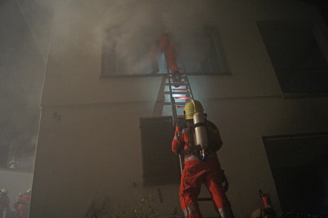 Die Feuerwehrmänner retten einen Eingeschlossenen im Haus mit Hilfe einer Leiter.