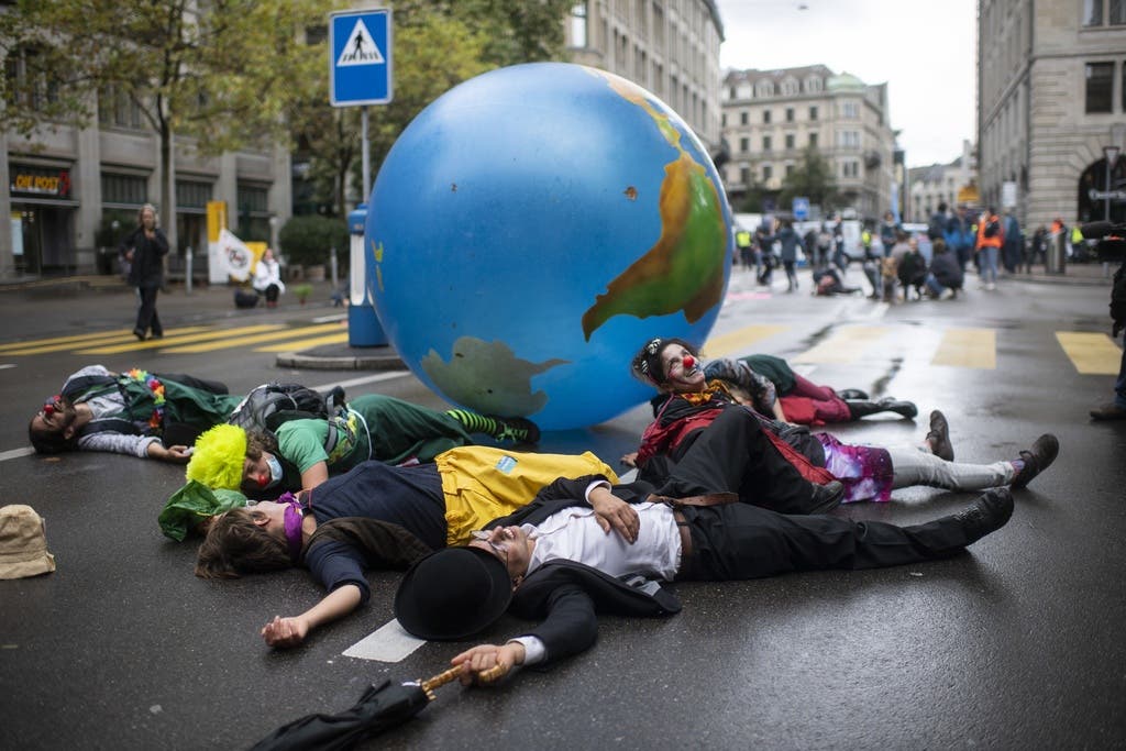 Verkleidete Menschen legten sich auf die nasse Strasse, um für mehr Klimaschutz zu werben.