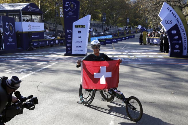epa09569952 Marcel Hug of Switzerland holds up his flag after winning the men?ïs wheelchair division of the 2021 TCS New York City Marathon in New York, New York, USA, 07 November 2021. EPA/Peter Foley