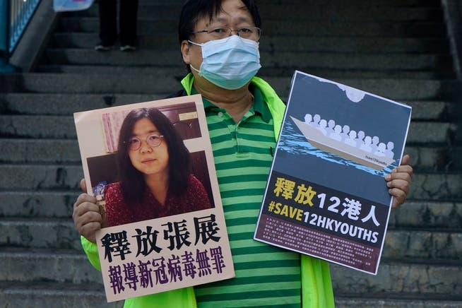 Ein Unterstützer hält in Hongkong ein Plakat mit Zhang Zhans Foto in die Kameras.