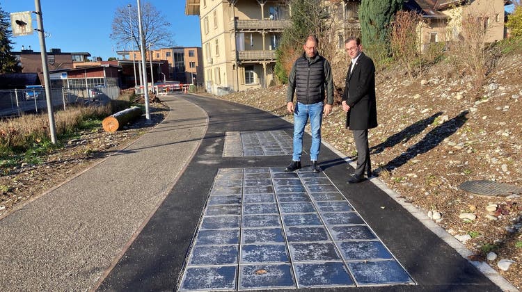 Gemeinderat Drin Alaj (rechts) und Projektleiter Antonio Milone bei den in die Fahrbahn eingelassenen Solarzellen aus wiederverwertetem Kunststoff. (Bild: PD)