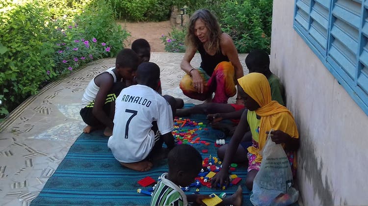 Marielle Furter spielt und lernt mit den Kindern im Senegal. Im Hintergrund der blühende Garten, den sie mit ihren Helfern angepflanzt hat. (zvg)