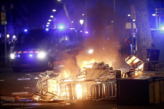 Szene mitten in Barcelona: Umgekippte Stühltürme als Barrikaden und die Polizei mit Blaulicht im Anmarsch.