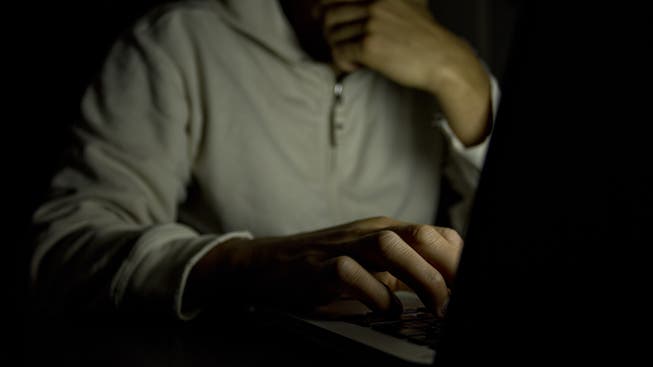 Anonymer Mann nachts mit einem Laptop.