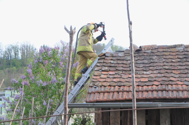 Ein Feuerwehrmann bei Löscharbeiten am Dach des Schopfes. 