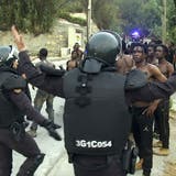 Polizisten der spanischen Guardia Civil drängen Migranten zurück. (Keystone)