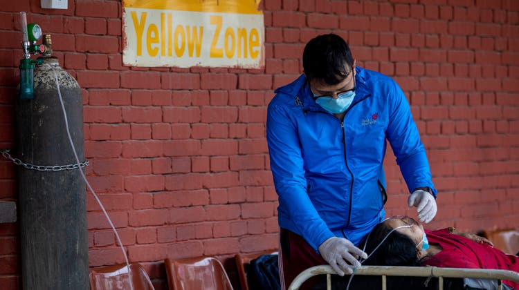 Eine Coronapatientin wartet vor einem Spital in Kathmandu darauf, dass sie gegen das Virus behandelt werden kann. (Keystone)