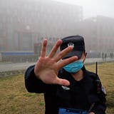 Ein Sicherheitswärter hält Journalisten vor dem Wuhan Institute of Virology (WIV) zurück. Hinten erhält eine Delegation der WHO Zutritt.