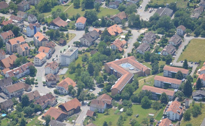 Luftaufnahme des Dorfzentrums Bettlach mit dem markanten Altersheimbau mit verglastem Innenatrium. 