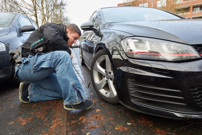Ein Polizist untersucht ein getuntes Auto auf illegale Bauteile. (Symbolbild)