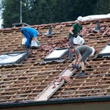 Dachdecker entfernen zerstörte Ziegel von einem Wolhuser Dach. (Bild: Eveline Beerkircher (29. Juni 2021))
