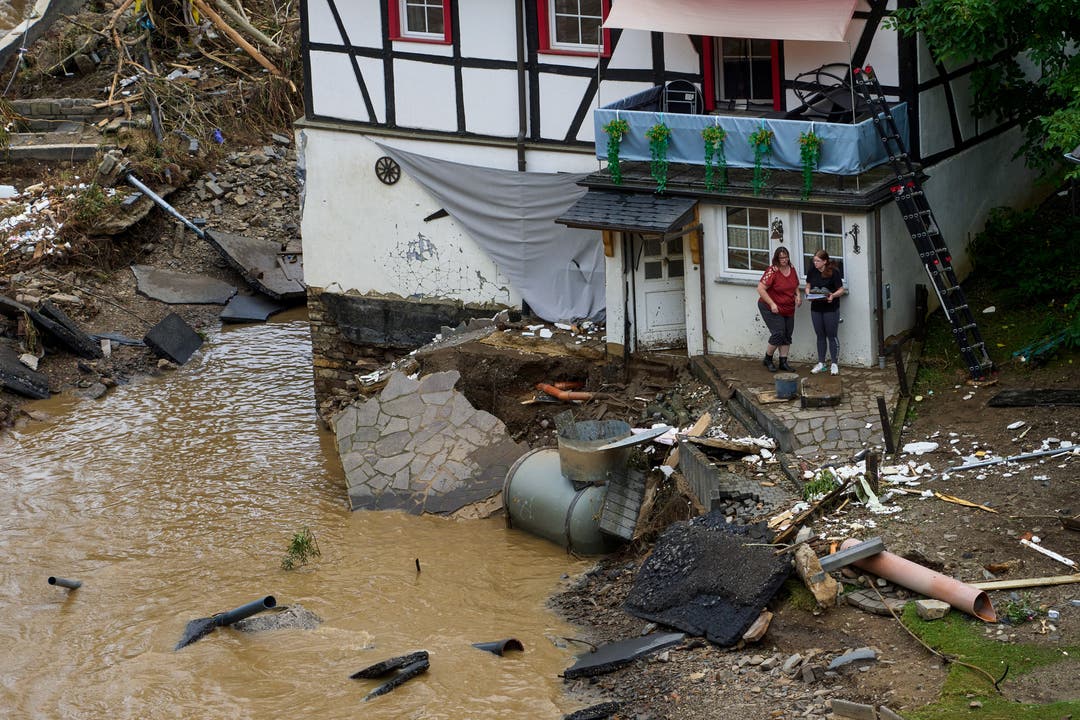 Rheinland-Pfalz, Schuld: Zwei Frauen stehen neben Trümmern vor einem Haus in dem Ort im Kreis Ahrweiler am Tag nach dem Unwetter mit Hochwasser. Mindestens sechs Häuser wurden durch die Fluten zerstört.
