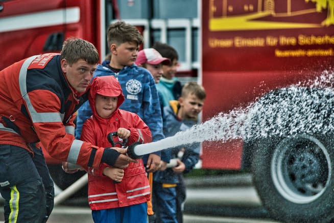 Offizier Thomas Haag zeigt den Kindern, wie man einen Feuerwehrschlauch benutzt.