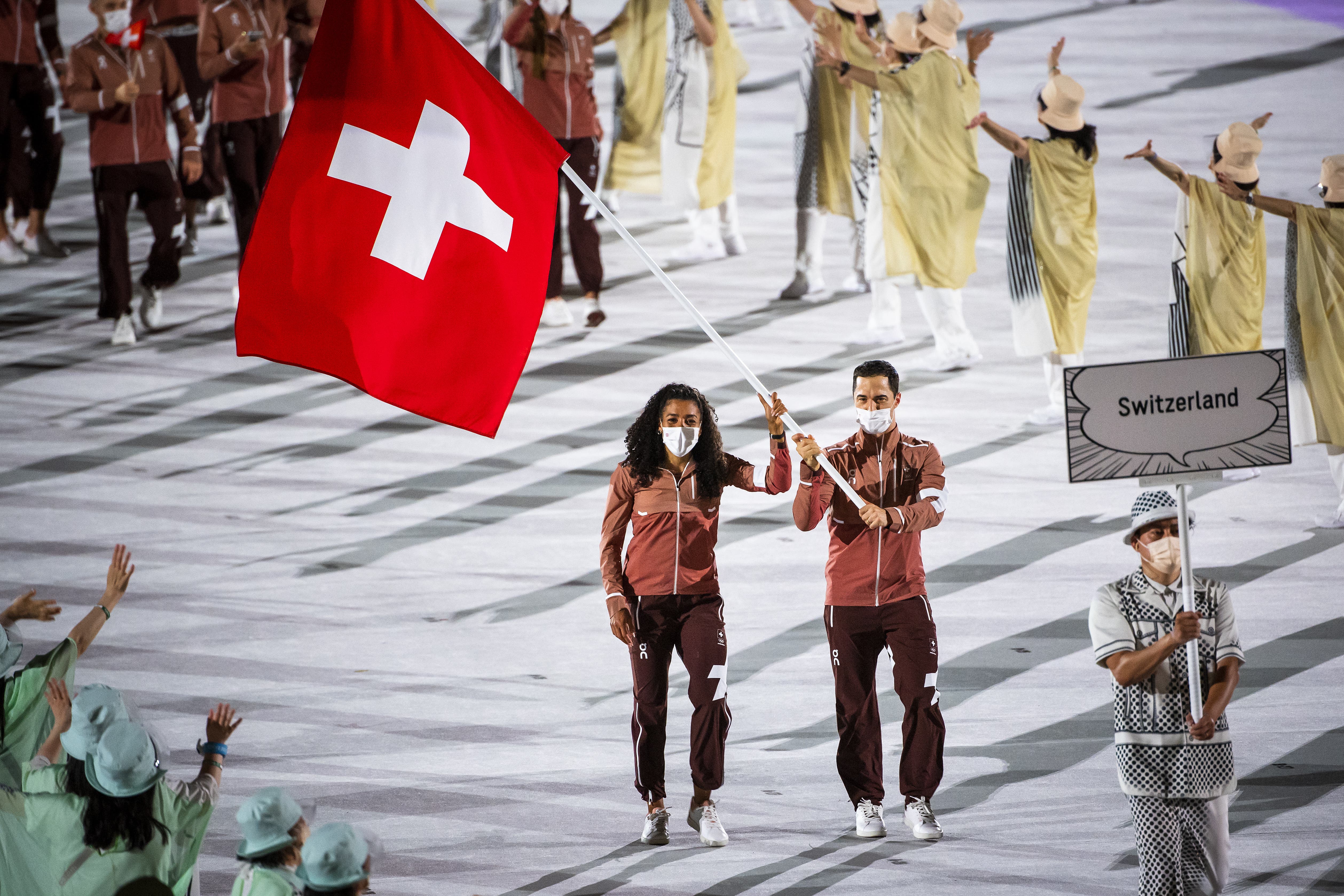 Die Schweizer Fahnenträger Mujinga Kambundji und Max Heinzer tragen stolz die rot-weisse Flagge ins Stadion.