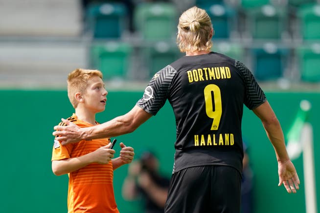 Ein Fan rennt auf das Spielfeld um Dortmunds Stürmer Erling Haaland um ein Autogramm zu bitten.