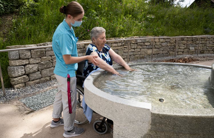Bewohnerin Margrit Isler, 83, zeigt vor, wie der neue Brunnen in der Kneippanlage bei der «Oberen Mühle» auch per Rollstuhl benutzt werden kann. Ann-Katrin Rosenauer, Pflegerin in Ausbildung, begleitet sie dabei.