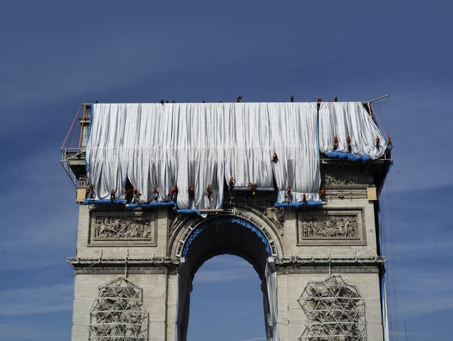 Industriekletterer umwickeln die Hülle des Arc de Triomphe mit roten Seilen. 