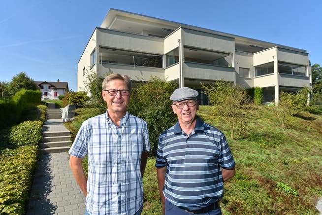 Stabübergabe von Heinz Bader (rechts) an Rainer Nussbaumer. Auf dem Bild der neuste Bau der Wohnbaugenossenschaft an der Stampfistrasse.
