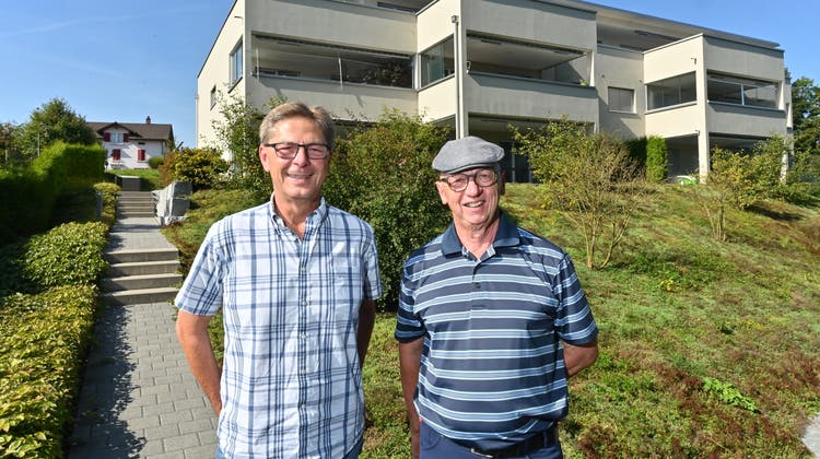 Stabübergabe von Heinz Bader (rechts) an Rainer Nussbaumer. Auf dem Bild der neuste Bau der Wohnbaugenossenschaft an der Stampfistrasse. (Bruno Kissling)