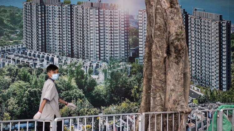 Die Aktien des chinesischen Immobilienriesen Evergrande haben massiv an Wert verloren. Im Bild: Ein Mann vor einer Werbung für das Wohnprojekt Emerald Bay in Hong Kong von Evergrande. (Jerome Favre / EPA)