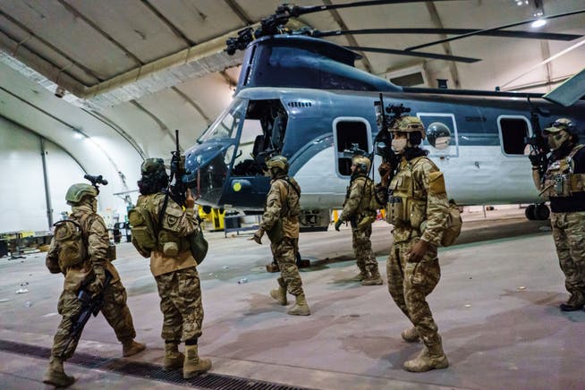 Taliban-Kämpfer am Flughafen von Kabul, vor einem flugunfähigen Helikopter.