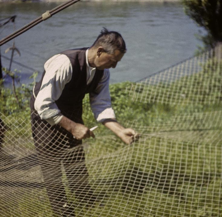 Ein Berufsfischer aus Birsfelden flickt sein Netz.