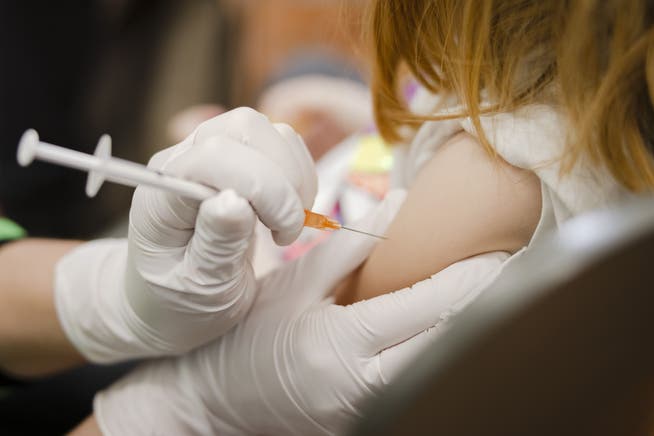 Eine Pflegefachfrau spritzt einem Kind eine Covid-19 Impfung.