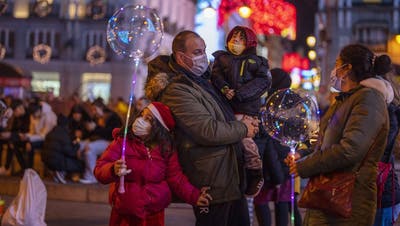 Mit Schutzmaske: eine Familie im weihnachtlich beleuchteten Madrid. (Keystone)