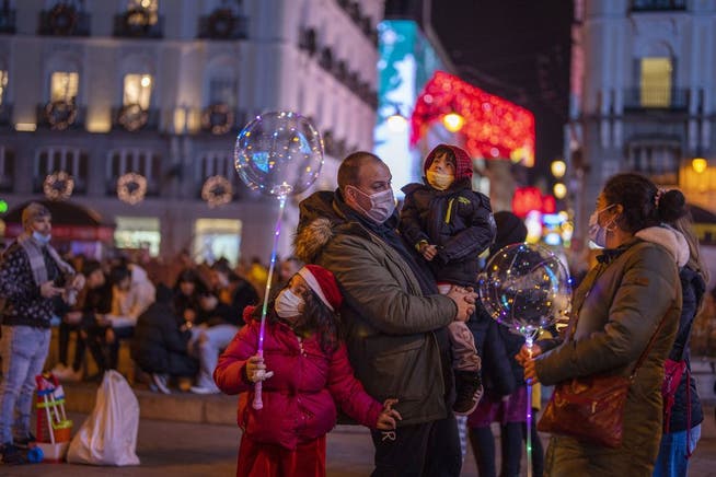 Mit Schutzmaske: eine Familie im weihnachtlich beleuchteten Madrid.