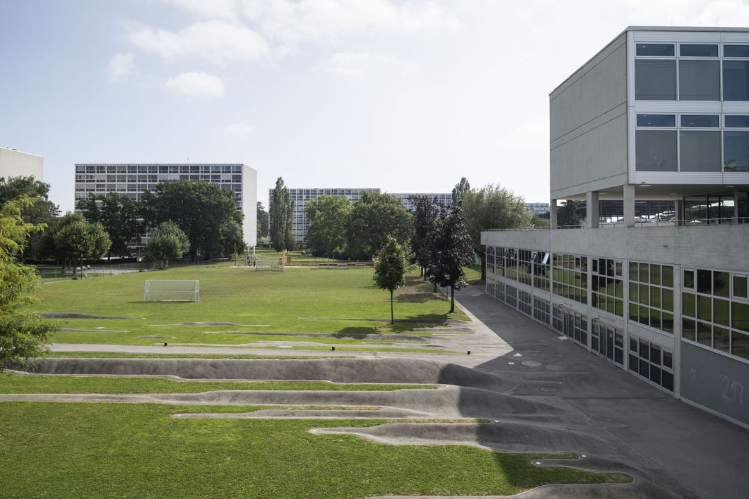 Wohnhäuser, Grünfläche und das Schulhaus Meyrin Boudines auf der rechten Seite. 