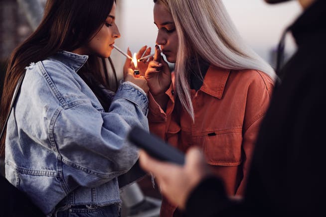 Out oder in? Zwei junge Frauen zünden sich Zigaretten an (Symbolbild).