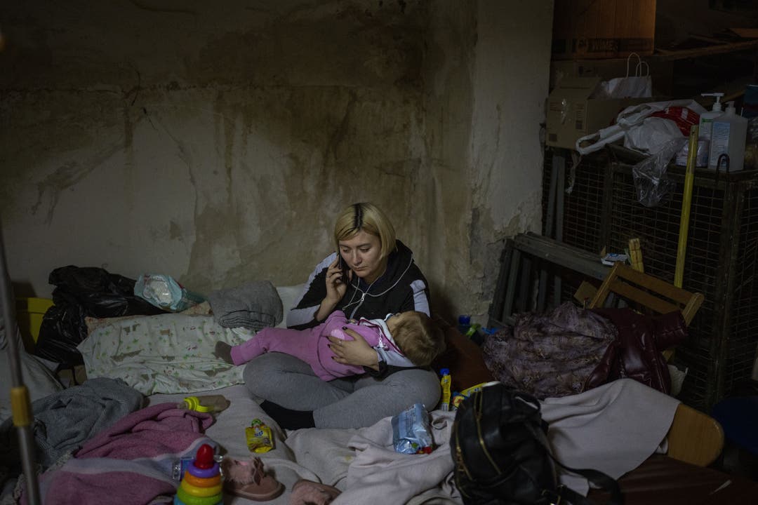 Eine ukrainische Frau mit ihrem kranken Kind telefoniert in einem zum Bunker umfunktionierten Keller eines Kinderhospitals in Kiew.
