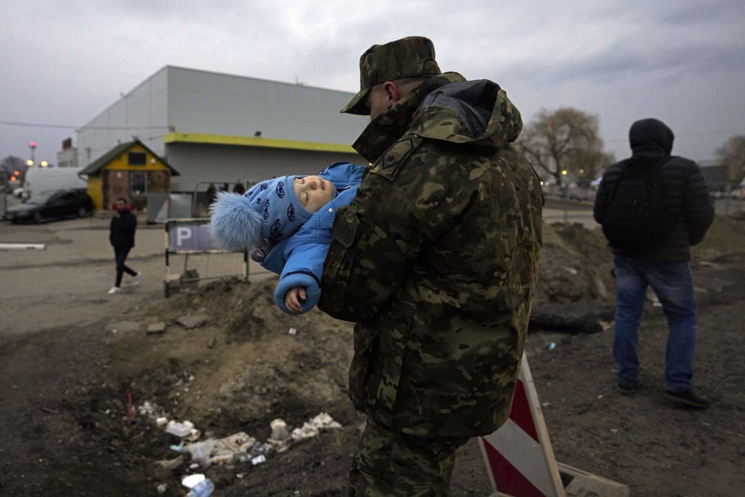 Ein polnischer Grenzsoldat trägt ein ukrainisches Flüchtlingskind über die GRenze bei Medyka (Polen).