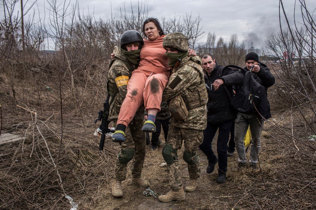 Ukrainische Soldaten helfen einer Frau über einen improvisierten Pfad aus der Stadt Irpin in der Nähe Kiews.