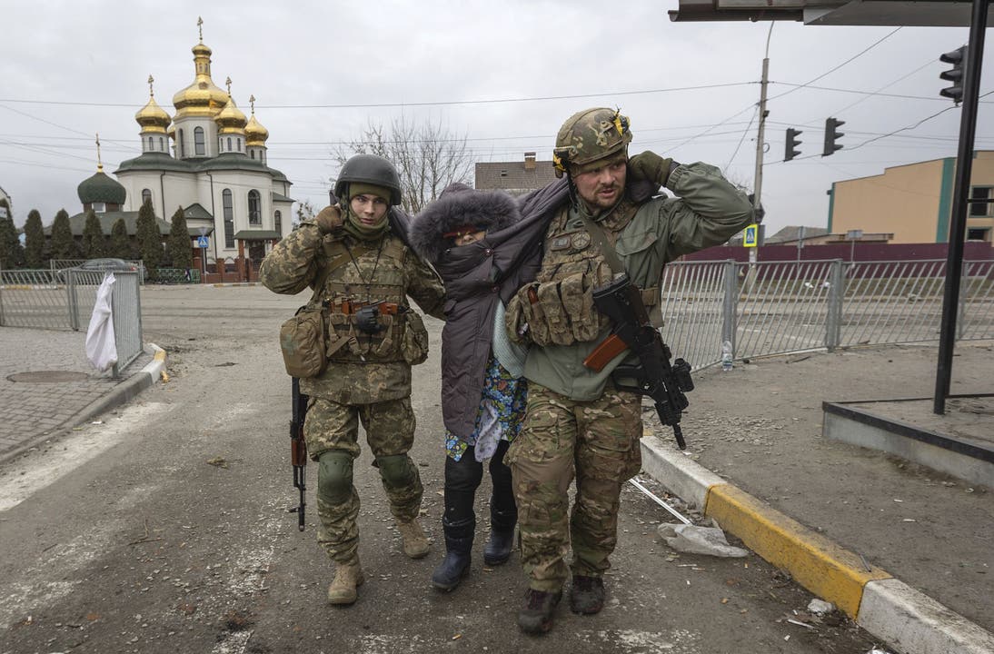 Ukrainische Soldaten helfen einer Frau in der ukrainischen Stadt Irpin. 