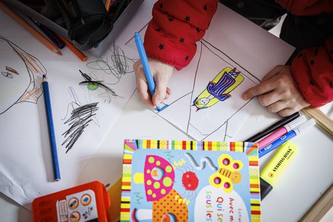 Ein Kind aus der Ukraine beschäftigt sich mit Zeichnen, während sich seine Familie bei einem Bundesasylzentrum registriert.