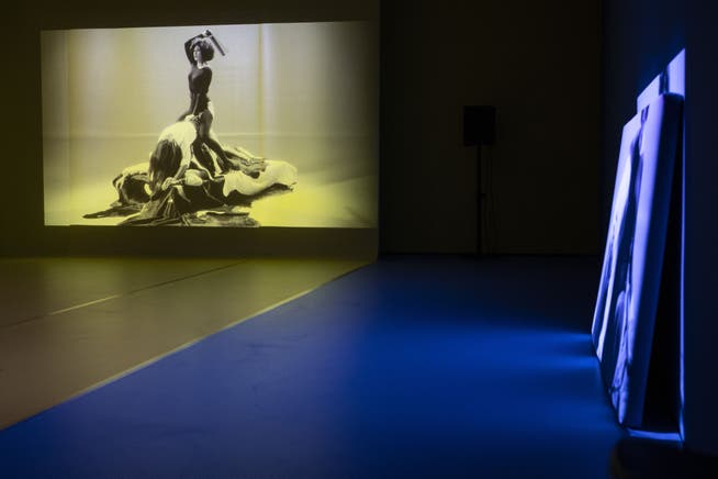 Auf drei Wänden in einem rot-gelb-blau gehaltenen Raum laufen die drei Videoprojektionen von Alexandra Bachzetsis' Werk «2020: Obscene».