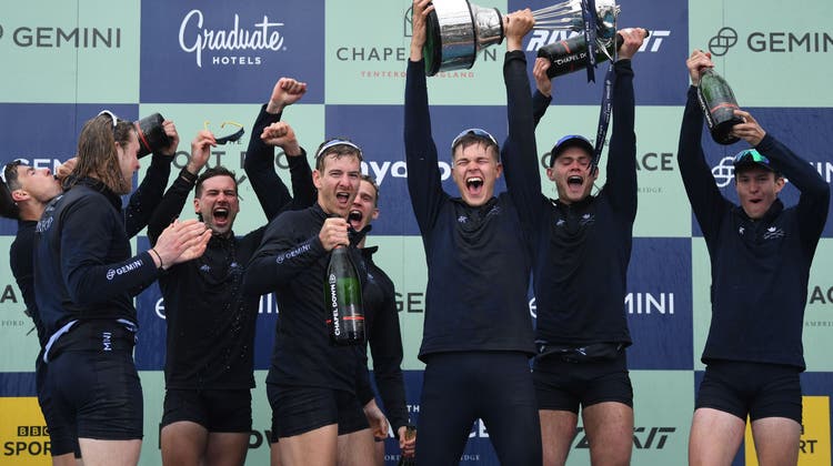 Roman Röösli (ganz links) und Barnabé Delarze (Mitte mit der Champagnerflasche) feiern den Sieg mit der Universität Oxford. (Neil Hall / EPA)