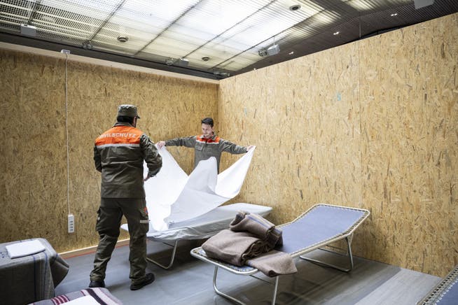 Menschen vom Zivilschutz helfen im Aufbau von Betten und Trennwänden in der Saalsporthalle für die kurzfristige Unterbringung von Geflüchteten aus der Ukraine.