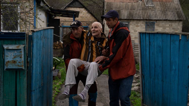 Zwei Helfer evakuieren einen alten Mann aus dem  Dorf Chasiv Yar im Donbass. Die Schlacht um die ostukrainische Region könnte zur entscheidenden dieses Krieges werden. (Keystone)