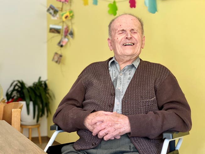 Martin Eugster sitzt im Aktivierungsraum im Alterswohn- und Pflegeheim Weiherwies in Grub AR und lächelt mit geschlossenen Augen in die Kamera.