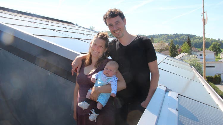 Mirjam und Mario Roost mit Nina zeigen die Solarzellen auf dem Dach ihres Hauses in Hägglingen. Diese liefern knapp viermal so viel Strom, wie die Familie braucht. Den Rest können sie den Nachbarn verkaufen. (Andrea Weibel)