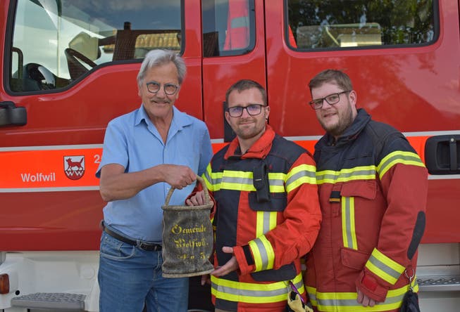 Klaus Schläfli überreicht den Löscheimer an Daniel Keller und David Portmann von der Feuerwehr Wolfwil (v.l.).