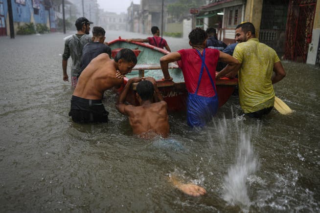 Helfende stossen ein Boot durch die Strassen Havannas, um Nachbarn zu retten.