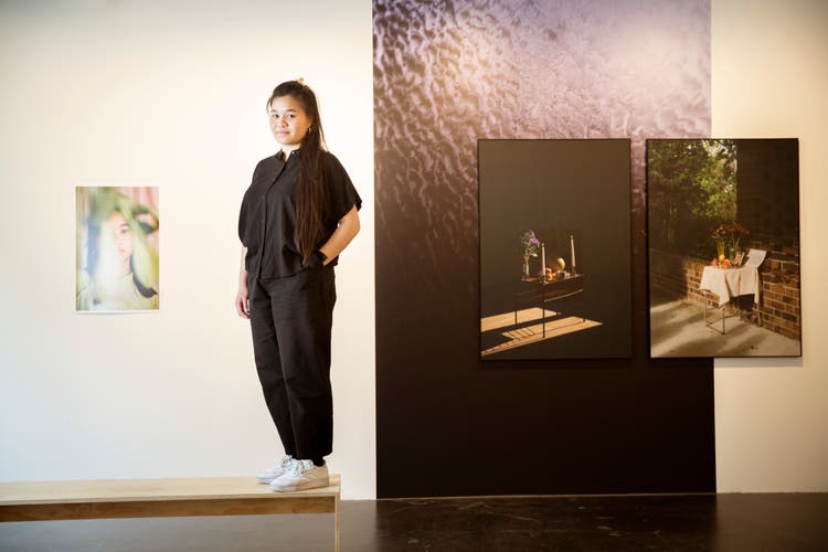 Thi My Lien Nguyen in ihrer Ausstellung im Raum für Fotografie der Coalmine in Winterthur. Rechts aussen der Altar für ihren Grossvater, daneben der Altar zur Einweihung ihres Ateliers. Links ist ein Porträt von Nguyens Cousine zu sehen.