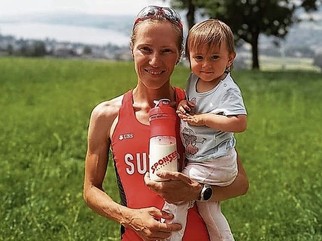 Natalia Gemperle präsentiert sich stolz im Nationaldress des Schweizer Berglaufteams und mit Tochter Luna im Arm .